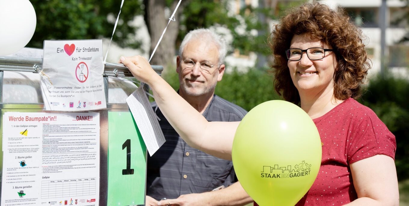 Frank Wiewiorra und Viola Scholz-Thies stehen vor einem Wassertank. Viola Scholz-Thies hält in ihrer Hand ein Luftballoon. 