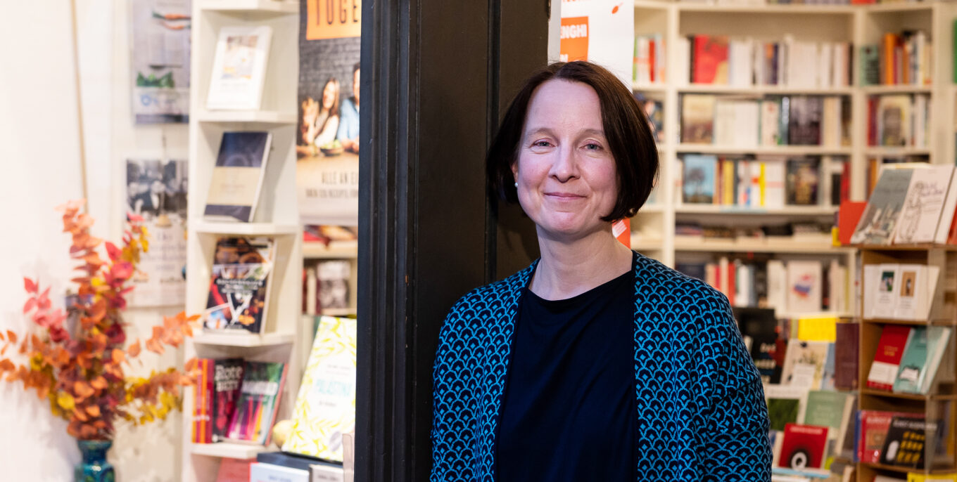 Inga Godolt schaut leicht lächelnd in die Kamera. Sie steht vor ihrem Buchladen. 