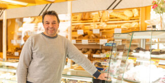 Bäckermeister Ralf Rajemann in der Halbtotalen steht im Verkaufsraum seiner Bäckerei