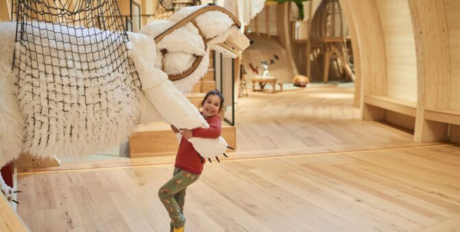 Ein Mädchen umarmt eine der Tierskulpturen in der Ausstellung Anoha – Die Kinderwelt des Jüdischen Museums Berlin