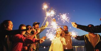 Eine grupper junger Menschen steht zusammen. Sie halten lange Wunderkerzen in die Mitte