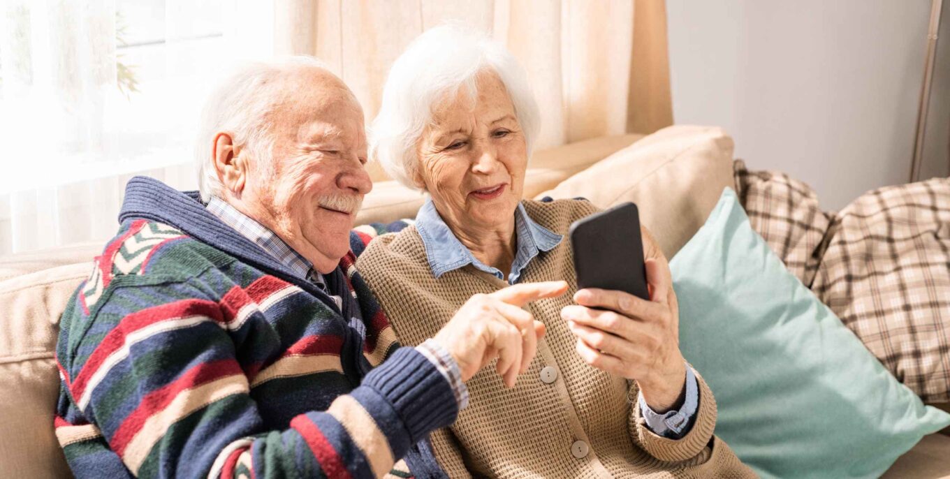 Porträt eines liebenswerten älteren Paares, das gemeinsam ein Smartphone benutzt
