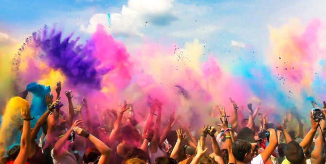 Holi Festival: Eine Menschenmasse wirft bunte Farbbeutel in die Luft.