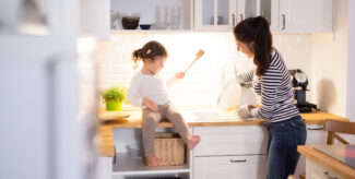 junge Frau und Kleinkind in der Küche kochen zusammen.