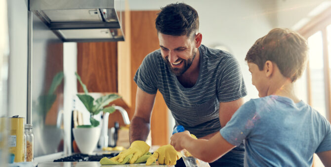 Vater und Sohn putzen zu Hause gemeinsam die Küchenarbeitsplatte