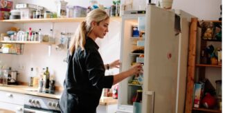 Lebensmittel lagern: Frau nimmt in der Küche eine Milchtüte aus dem Kühlschrank