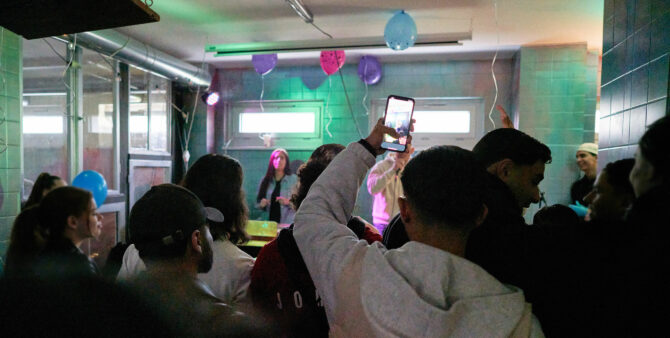 Impressionen von der Eröffnungsparty des Jugendkulturorts "Blocklab 447". Mehrere Jugendliche von hinten, die sich eine Rap-Performance anschauen.