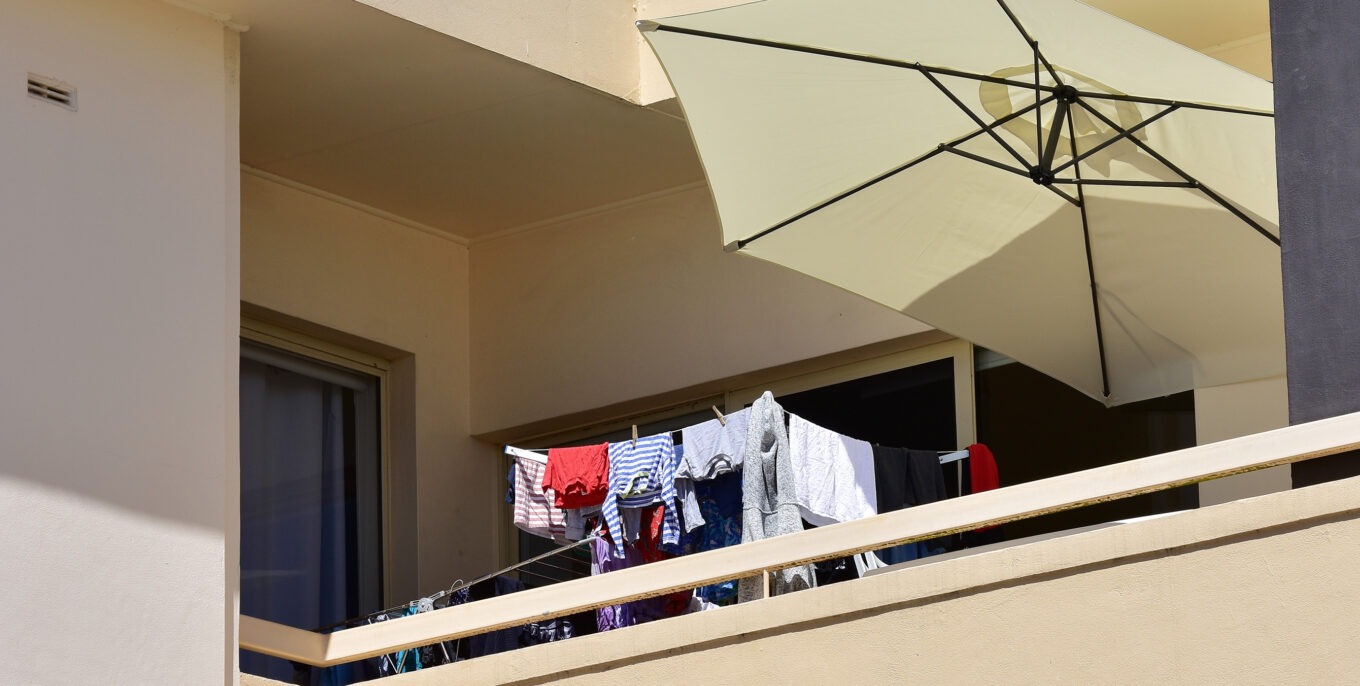 auf einem Balkon hängt Wäsche und steht ein Sonnenschirm