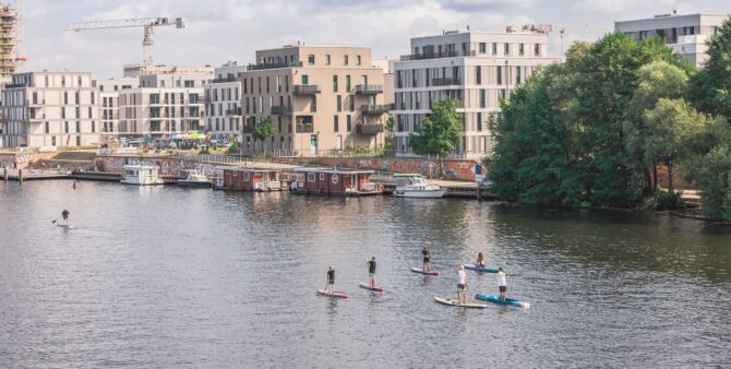 SUP an der Waterkant: Sechs Personen auf SUP-Boards während eines Gewobag-Kurses auf der Havel.