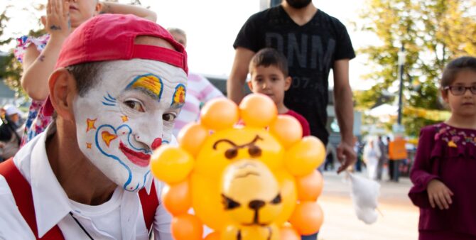 Gewobag Fest in der Falkenberger Chaussee: Ein Luftballon-Künstler mit bemaltem Clownsgesicht hält einen aus Luftballons geformten Löwenkopf in die Kamera.