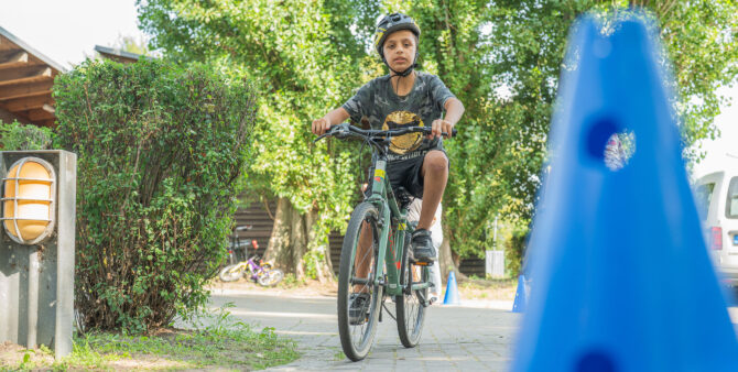 Ein Junge mit Helm fährt auf einem Fahrrad durch den Fahrrad-Parcours vor dem Jugendclub Heckerdamm. Foto: Felix Seyfert.