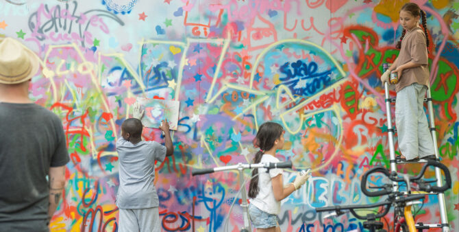 Drei Kinder bemalen eine Wand mit Spraydosen. Foto: Felix Seyfert