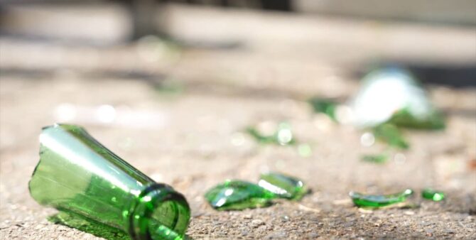 Eine Großaufnahme einer zerbrochenen Bierflasche, deren Scherben auf Betonboden liegen. Foto: Screenshot aus dem Musikvideo Zero Waste Heroes / Staaken Version