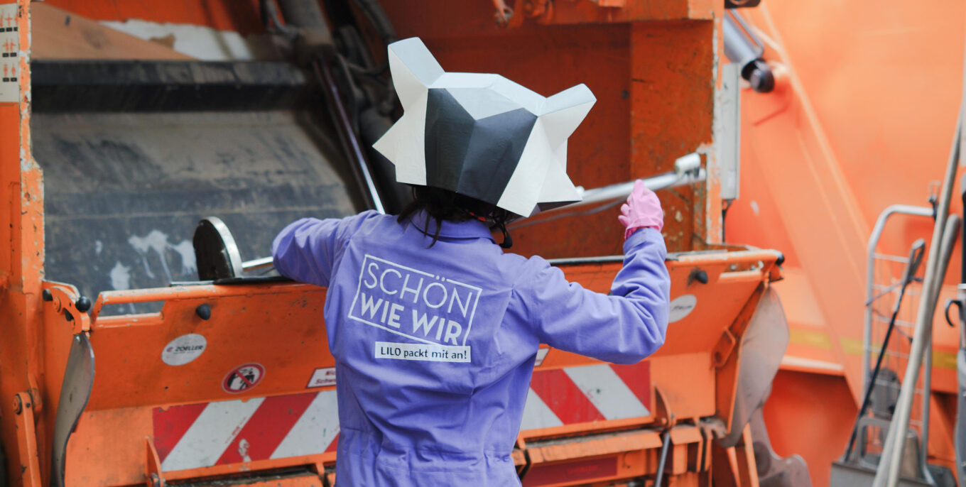 Das Maskottchen "Lilo" von der Bewegung "Schön wie wir" entsorgt eine alte Stehlampe in einem Müllwagen der Berliner Stadtreinigung. Foto: Schön wie wir