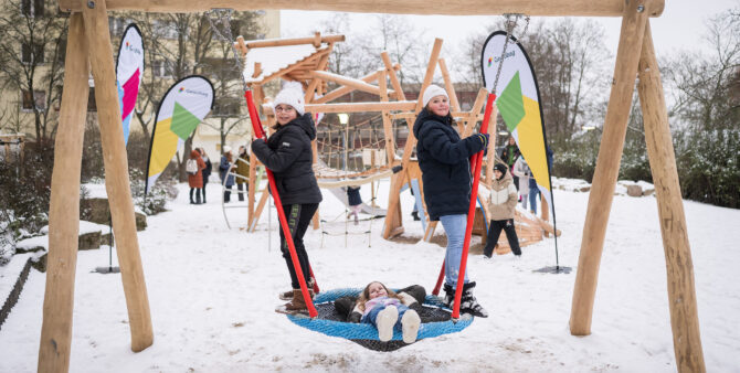 Drei Mädchen auf einer Netzschaukel - zwei stehend, eins in der Mitte liegend. Szenerie auf einem verschneiten Spielplatz. Foto: Moritz Eden/City-Press GmbH