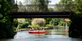 Zwei Kanus mit je zwei InsassInnen in sommerlicher Atmosphäre au einem Flussabschnitt in Neu-Venedig. Foto: Imago