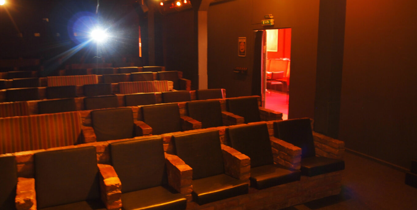 Der Kinosaal 2 im Sputnik Kino. Gemauerte Sitzbänke, dahinter der Schein des Projektors. 