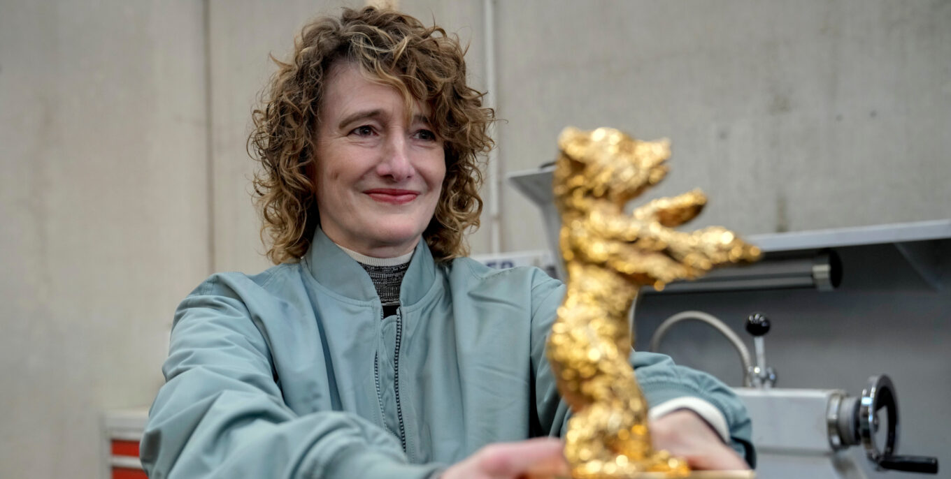 Frau hält einen Goldenen Bären, die begehrte Trophäe der Berlinale, mit einem glücklichen Ausdruck in den Händen.