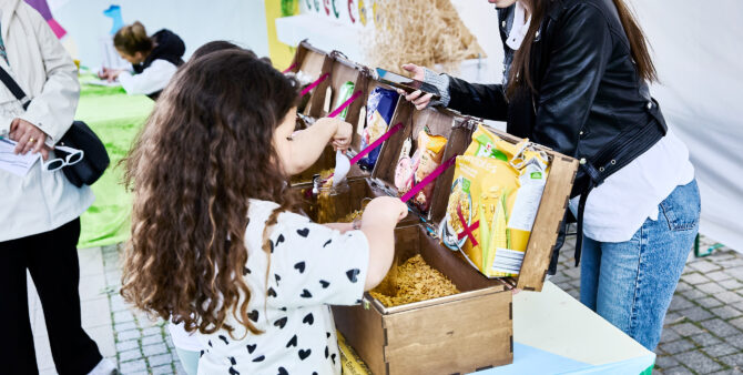 Aktion gegen Verpackungsmüll: Ein kleines Mädchen füllt lose Cornflakes aus einer Box in ein Glas. Foto: Felix Seyfert