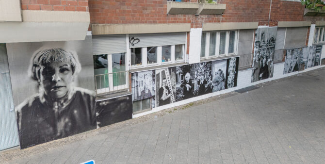 Eine Hauswand, die mit mehreren großen Schwarz-Weiß-Porträts beklebt ist. Foto: Felix Seyfert