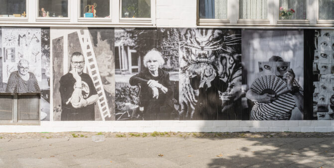 Fünf große Schwarz-Weiß-Porträts von Menschen in verschiedenen Posen an einer Hauswand. Foto: Felix Seyfert