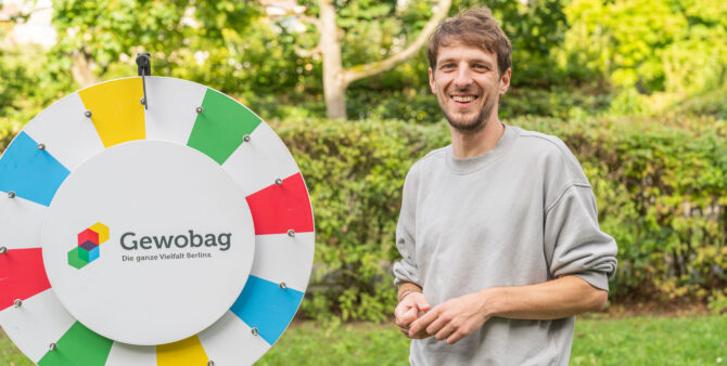 Ein Mann steht neben einem großen Glücksrad mit bunten Abschnitten und dem Logo der Gewobag. Foto: Felix Seyfert