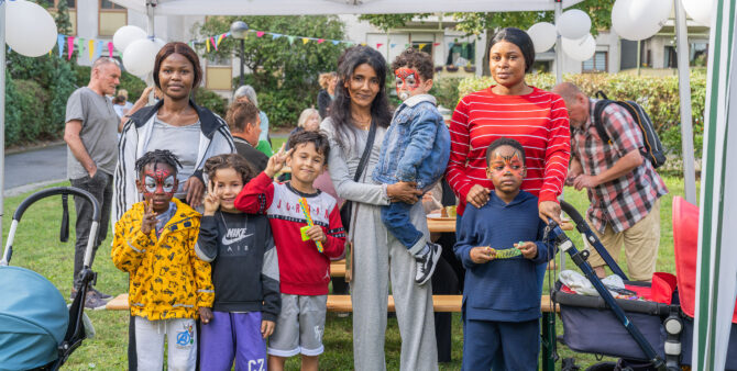 Eine Gruppe von Erwachsenen und Kindern steht unter einem Pavillon bei einer Outdoor-Veranstaltung, mit Luftballons im Hintergrund. Foto: Felix Seyfert
