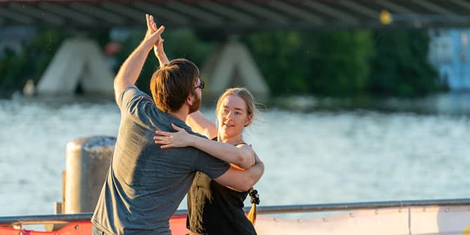 Ein junges Paar beim Standardtanz im Freien. Im Hintergrund ist ein großer Fluss zu erkennen. Foto: Ralph Maak
