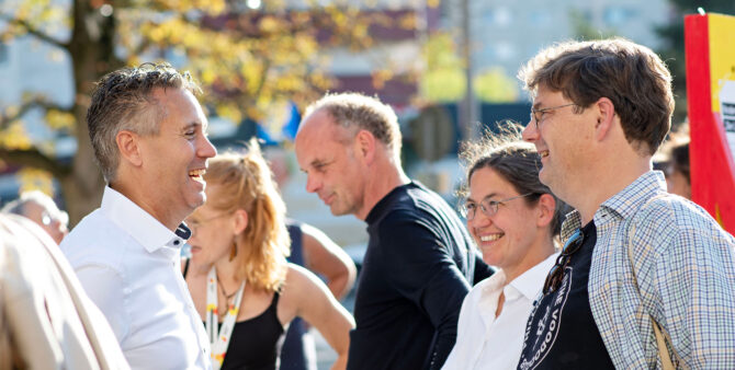 Szene eines Quartiersfest: Zwei Männer und eine Frau im Gespräch, alle lächelnd. Foto: Jennifer Sanchez