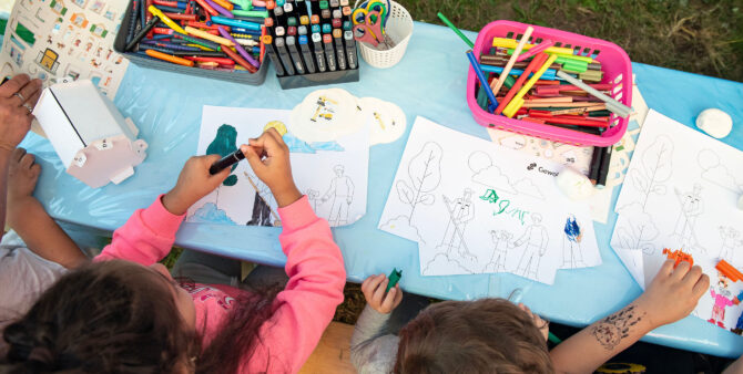 Ansicht von oben: Kinder sitzen an einem Tisch und malen Ausmalbögen aus. Foto: Jennifer Sanchez