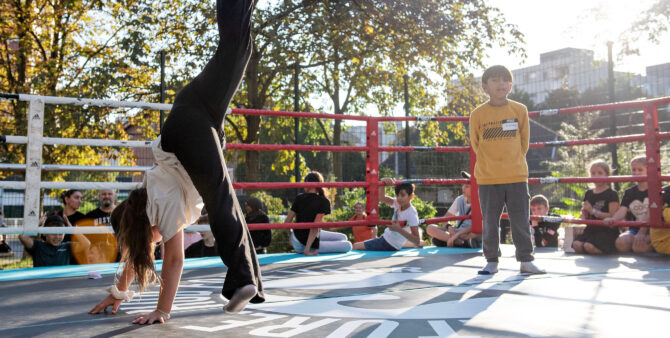 Ein Junge und ein Mädchen bei einem Tanzbattle in einem Boxring im Freien. Drumherum schauen Kinder zu. Foto: Jennifer Sanchez