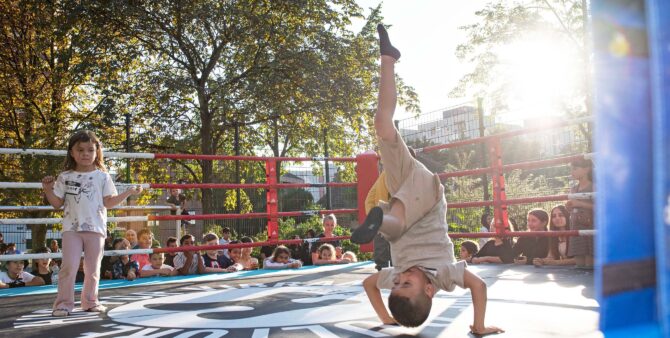 Ein Junge und ein Mädchen bei einem Tanzbattle in einem Boxring im Freien. Drumherum schauen Kinder zu. Foto: Jennifer Sanchez