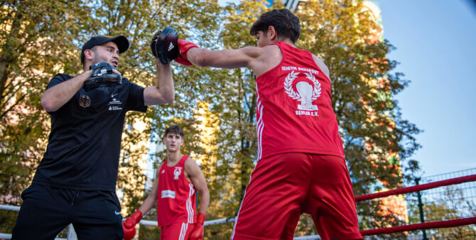 Szene einer Showeinlage: ein junger Boxer mit einem Trainer beim Training im Boxring, der im Freien aufgebaut ist. Foto: Jennifer Sanchez