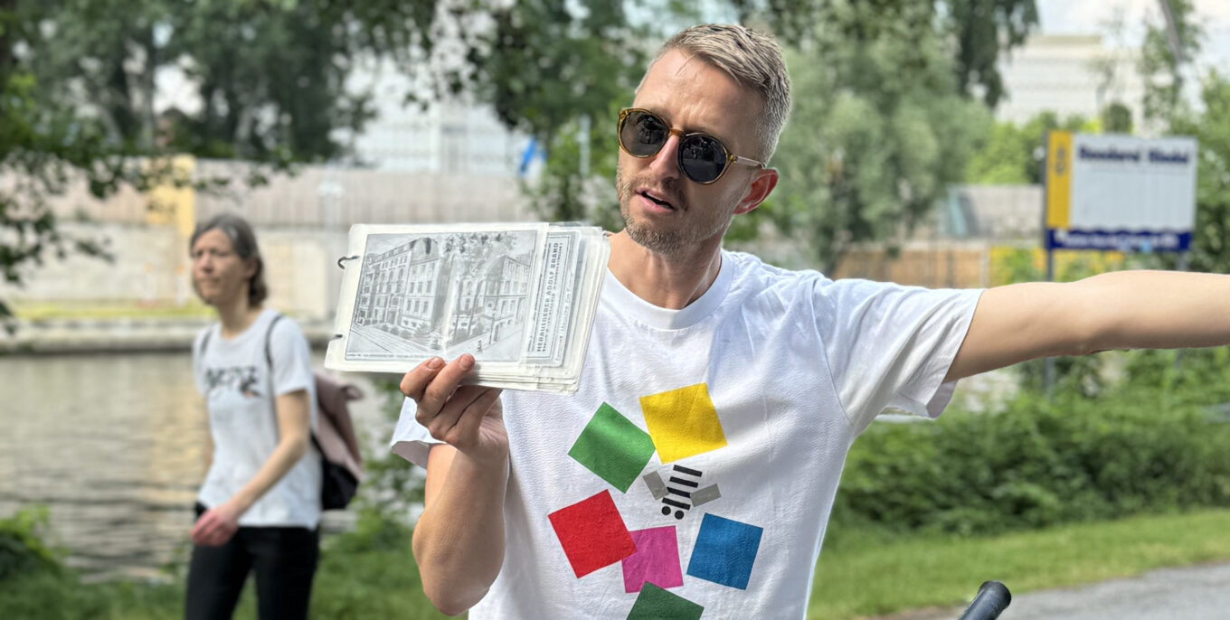 Stadtführer zeigt historische Fotos bei Tour entlang eines Kanals in Berlin.