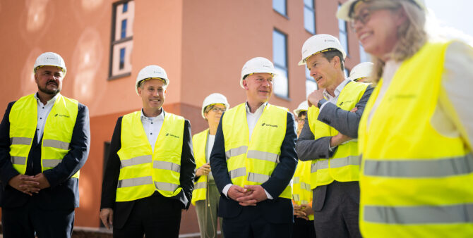 Eine Gruppe aus Männern und Frauen mit Bauhelmen und gelben Leuchtwesten während eines Baustellenrundgangs. Foto: City-Press GmbH