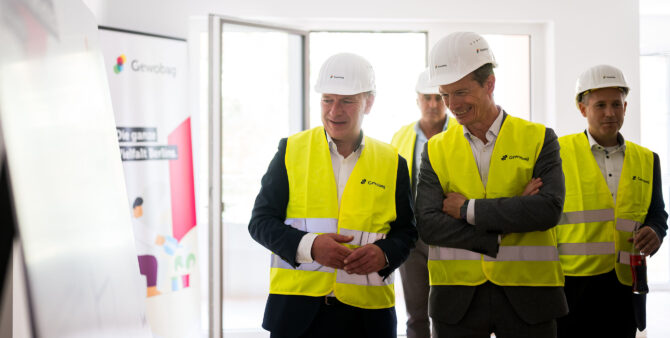 Vier Personen mit Bauhelmen und gelben Leuchtwesten bei der Besichtigung einer Musterwohnung. Foto: City-Press GmbH