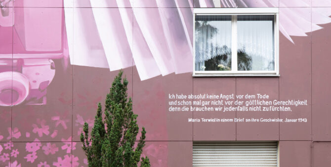 Großaufnahme einer bemalten Häuserfassade, auf der unter einem Fenster ein Schriftzug prangt: "Ich habe absolut keine Angst vor dem Tode und schon mal gar nicht vor der göttlichen Gerechtigkeit, denn die brauchen wir jedenfalls nicth zu fürchten."