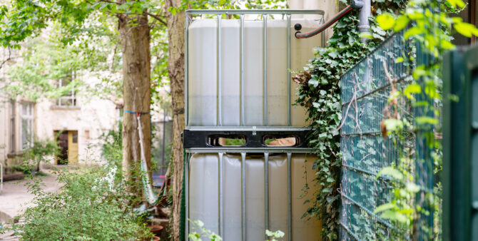 Eine Regentonne in einem begrünten Innenhof. Foto: Ralph Maak