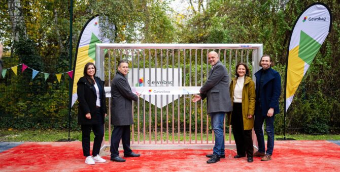 Pressefoto: Fünf Personen stehen vor einem Fußballtor auf einem Bolzplatz im Freien und lächeln in die Kamera. Zwei von ihnen durchschneiden ein Eröffnungsband, das zwischen den Pfosten des Fußballtores aufgespannt wurde. Foto: City-Press GmbH
