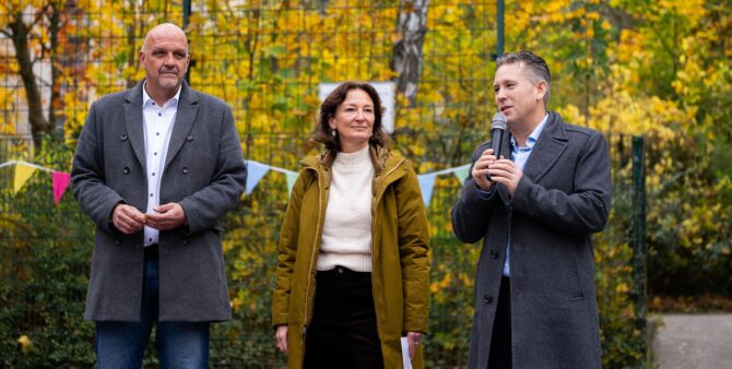 Zwei Männer und eine Frau bei einer Veranstaltung auf einem Bolzplatz im Freien. Einer der Männer spricht in ein Mikrofon. Foto: City-Press GmbH