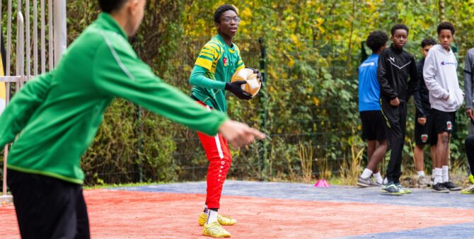 Ein Junge in Fußballbekleidung hält auf einem Bolzplatz einen Fußball in der Hand. Foto: City-Press GmbH
