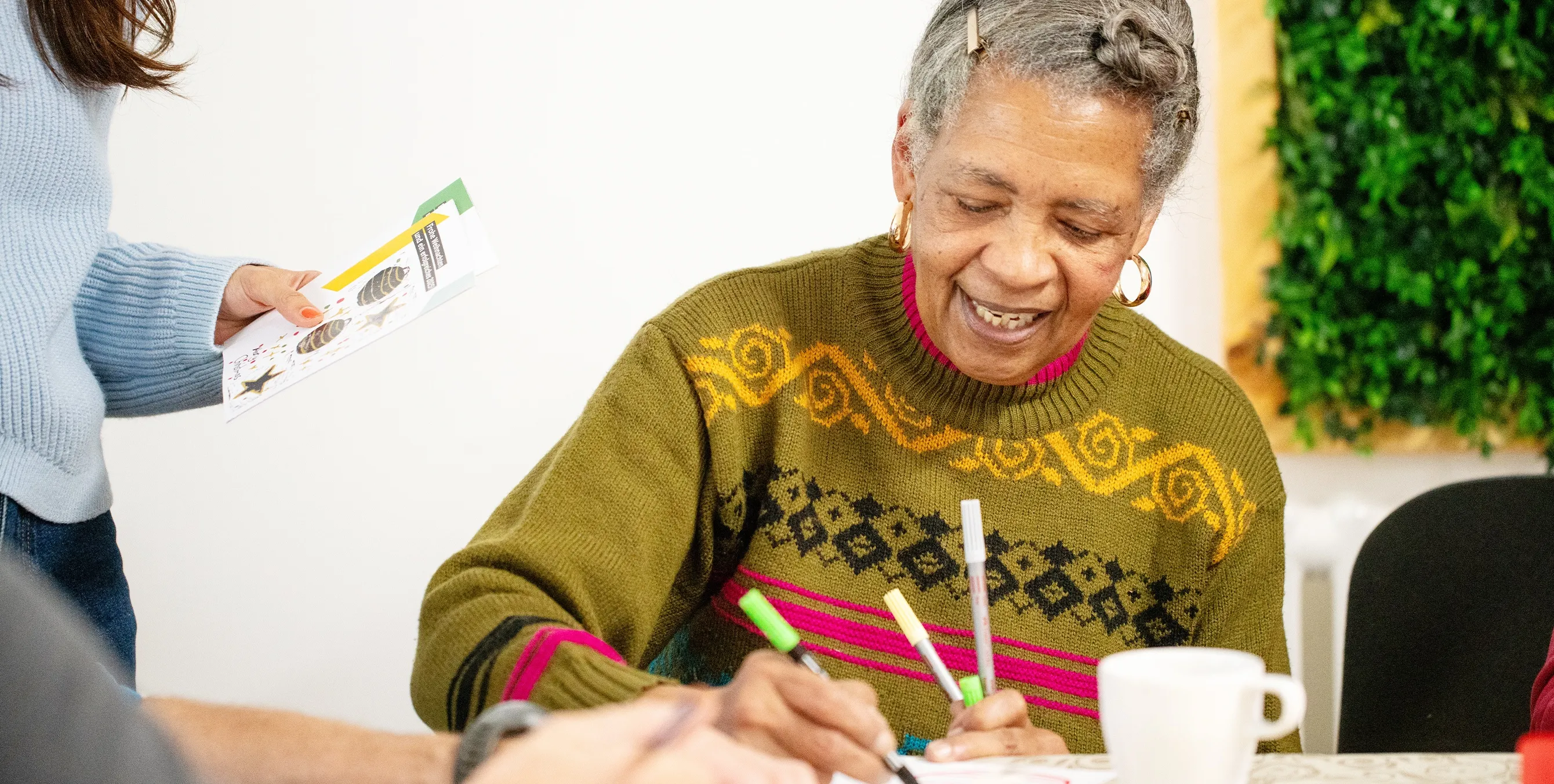 Großaufnahme: Eine älter Frau sitzt an einem Tisch und malt. Foto: Ralph Maak