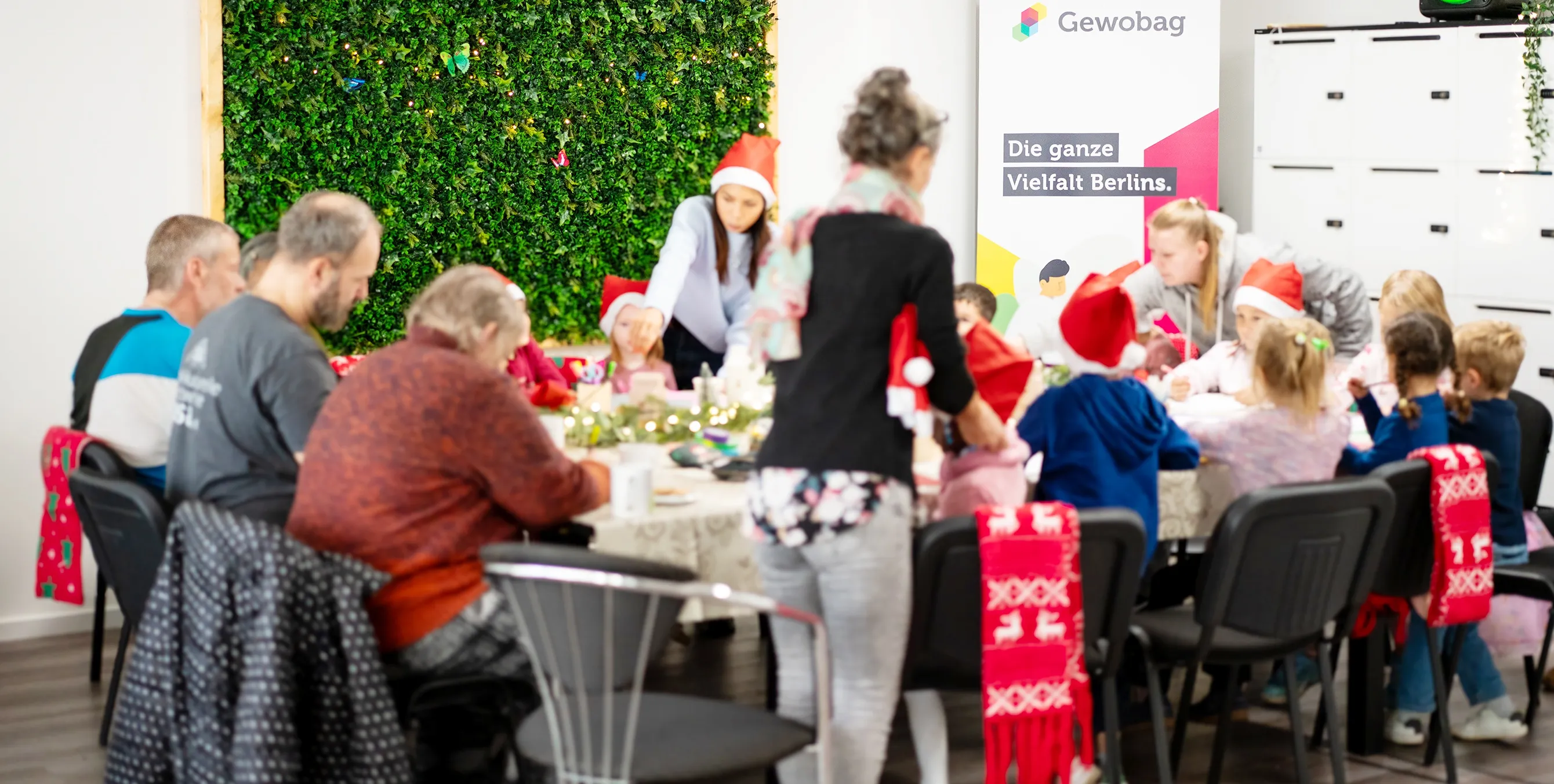 Kinder und Erwachsene sitzen an einem weihnachtlich geschmückten Tisch und malen. Foto: Ralph Maak