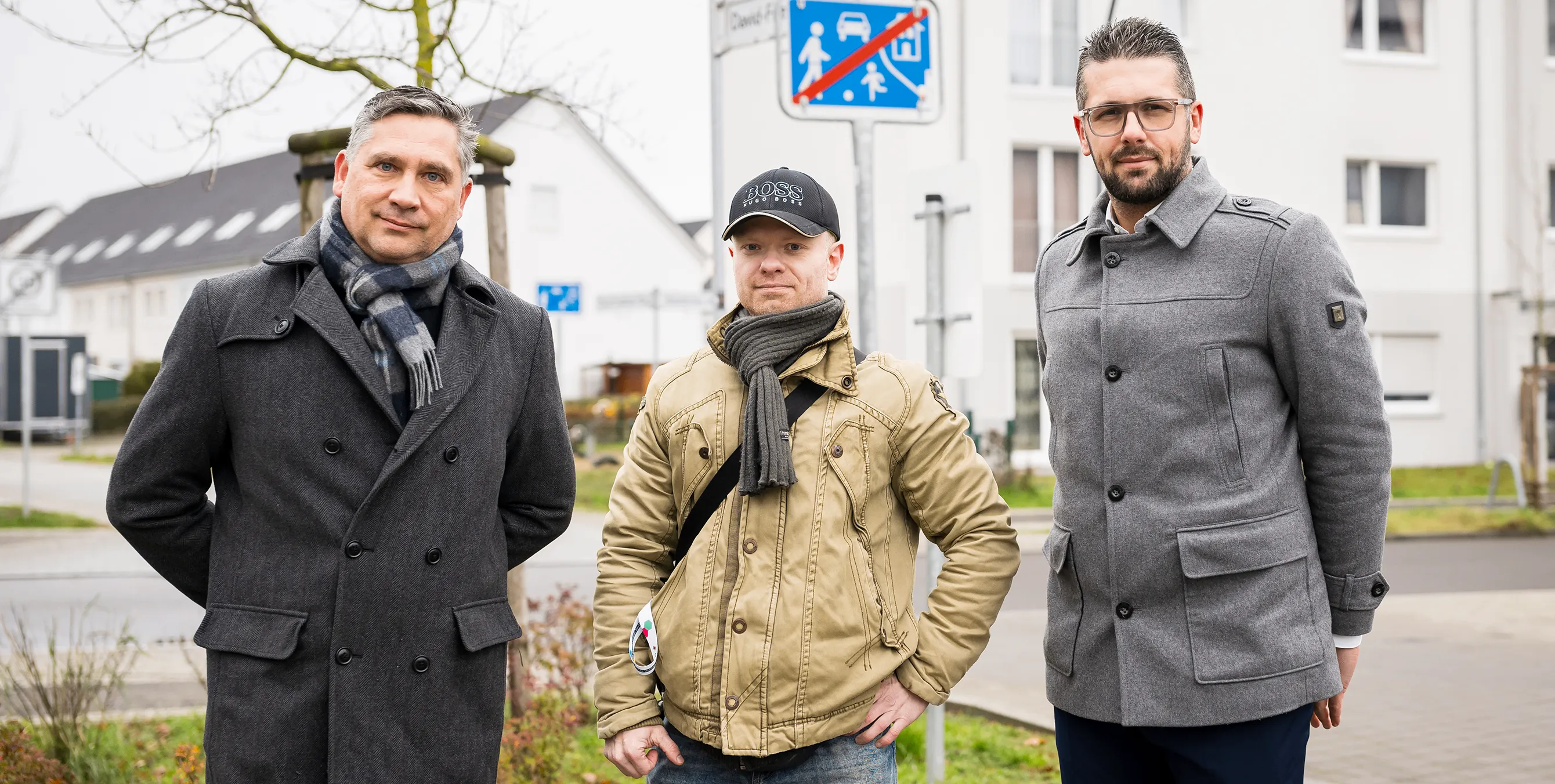 Drei Männer stehen in einem Wohnquartier und schauen für ein Gruppenbild in die Kamera. Foto: City-Press GmbH