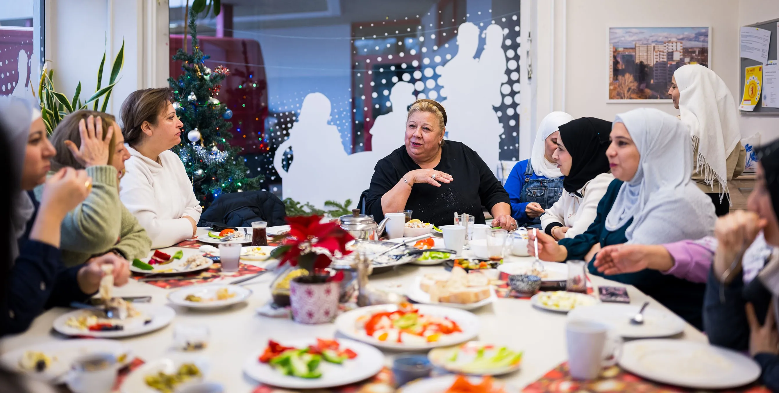 Acht Frauen sitzen gemeinsam an einem reichhaltig gedeckten Frühstückstisch in einem weihnachtlich geschmückten Raum und unterhalten sich. Foto: City-Press GmbH