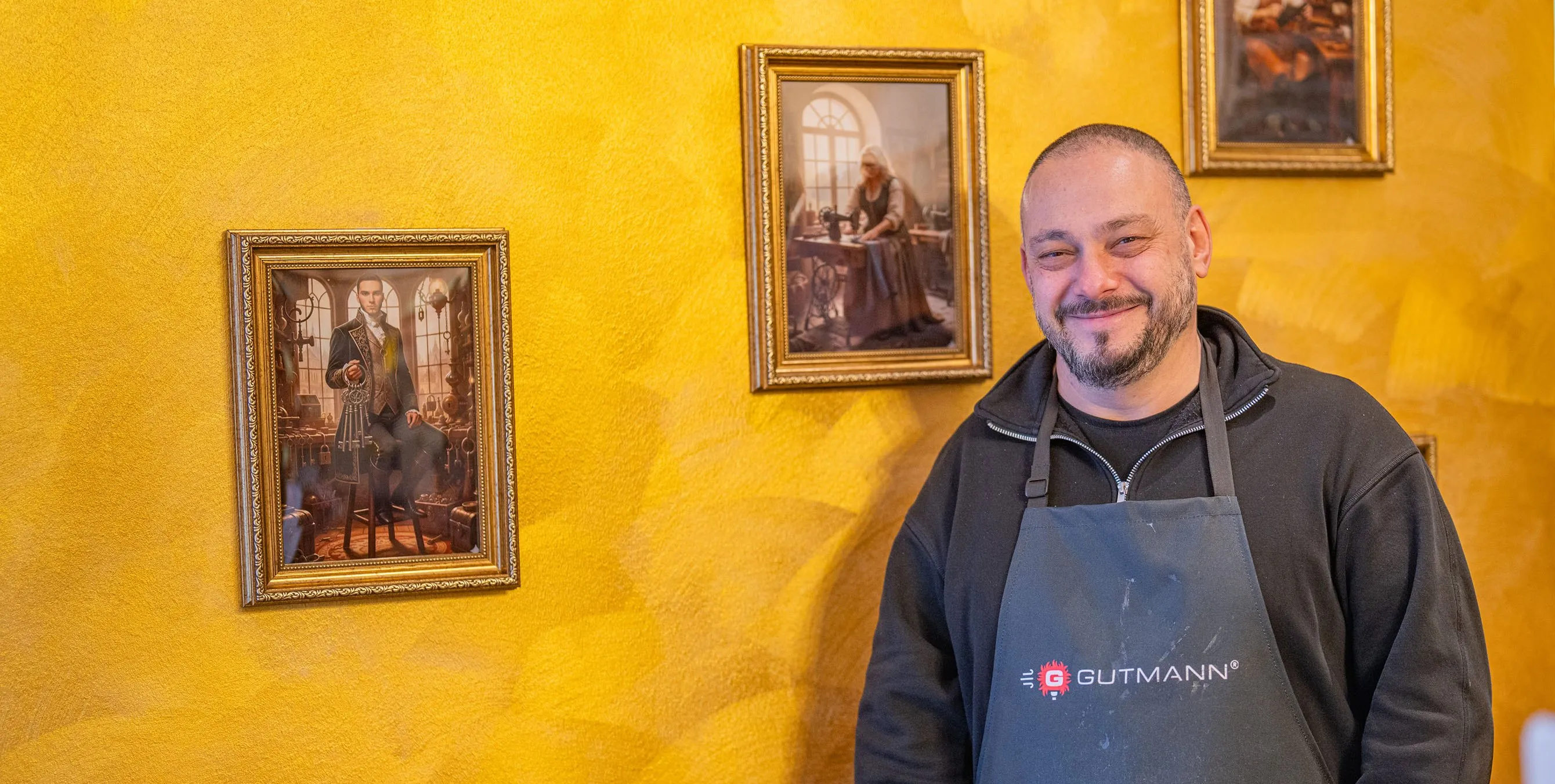 Ein lächelnder Mann steht vor einer goldfarbenen Wand, an der traditionelle Bilder hängen. Foto: Felix Seyfert