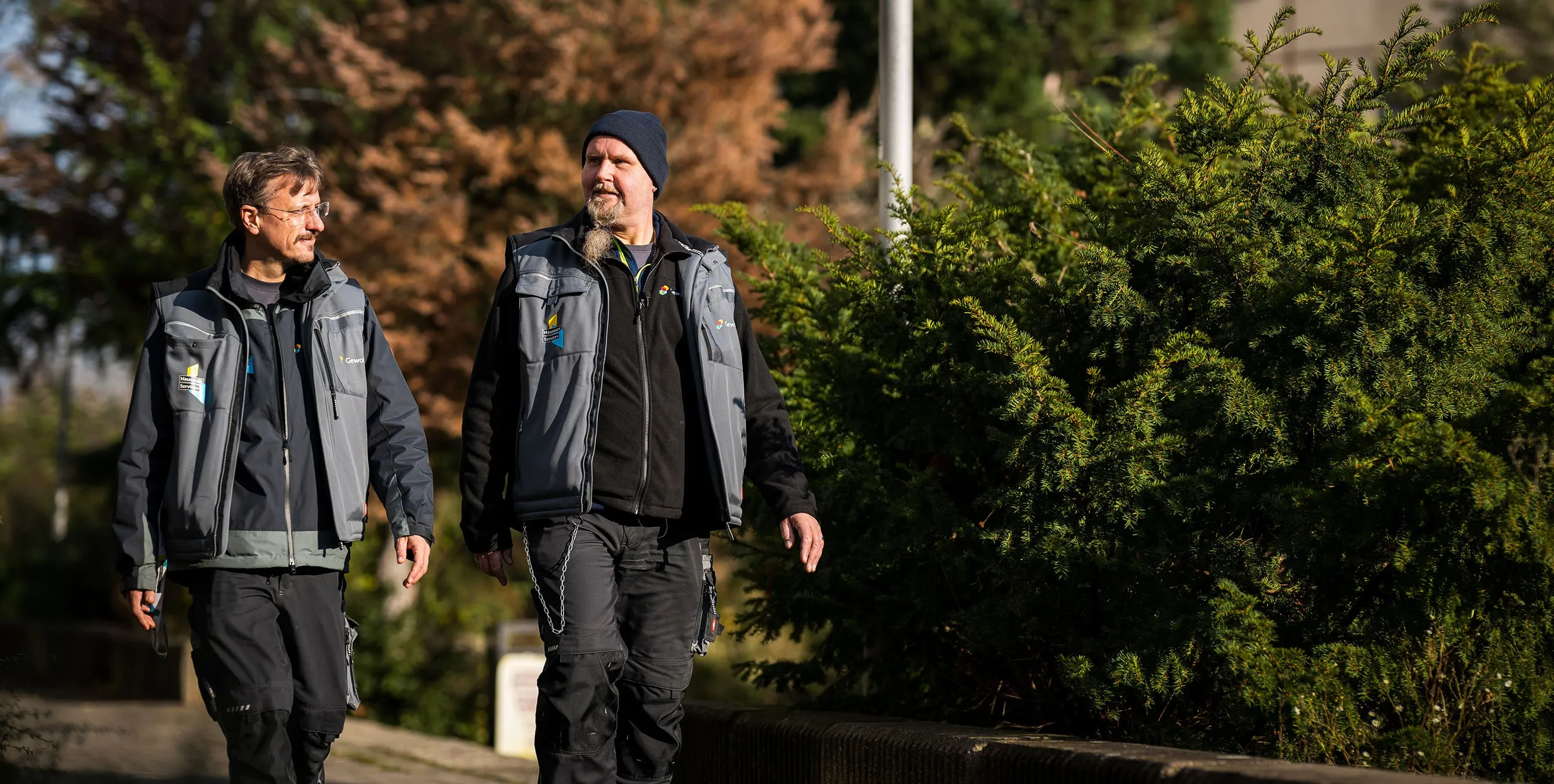 Zwei Hauswarte gehen nebeneinander durch ein Wohnquartier. Foto: City-Press GmbH