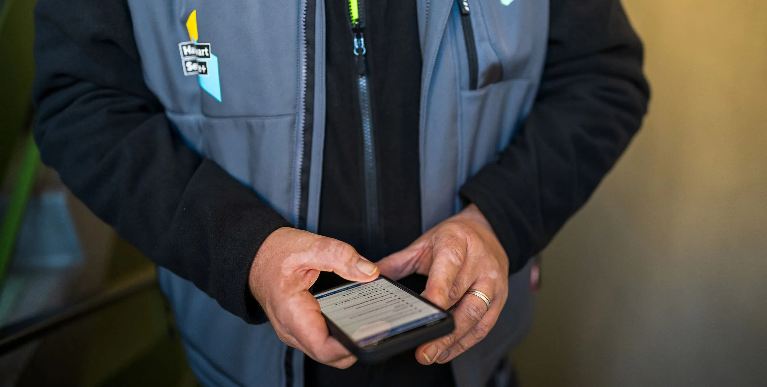 Großaufnahme: Ein Hauswart hält ein Smartphone in seinen Händen und gibt etwas in eine App ein. Foto: City-Press GmbH