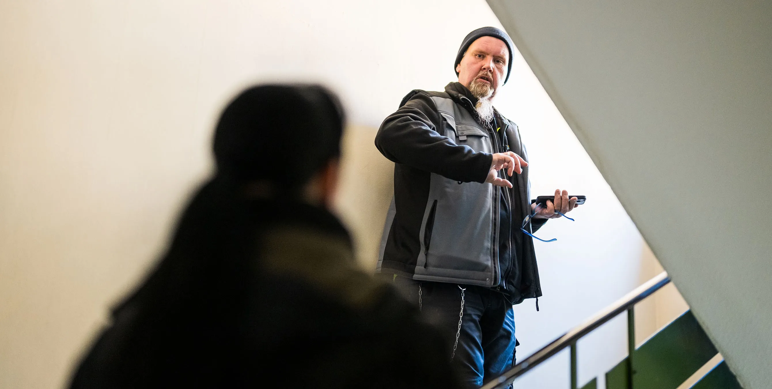 Ein Hauswart steht in einem Treppenhaus auf halber Treppe und unterhält sich mit einer anderen Person. Foto: City-Press GmbH