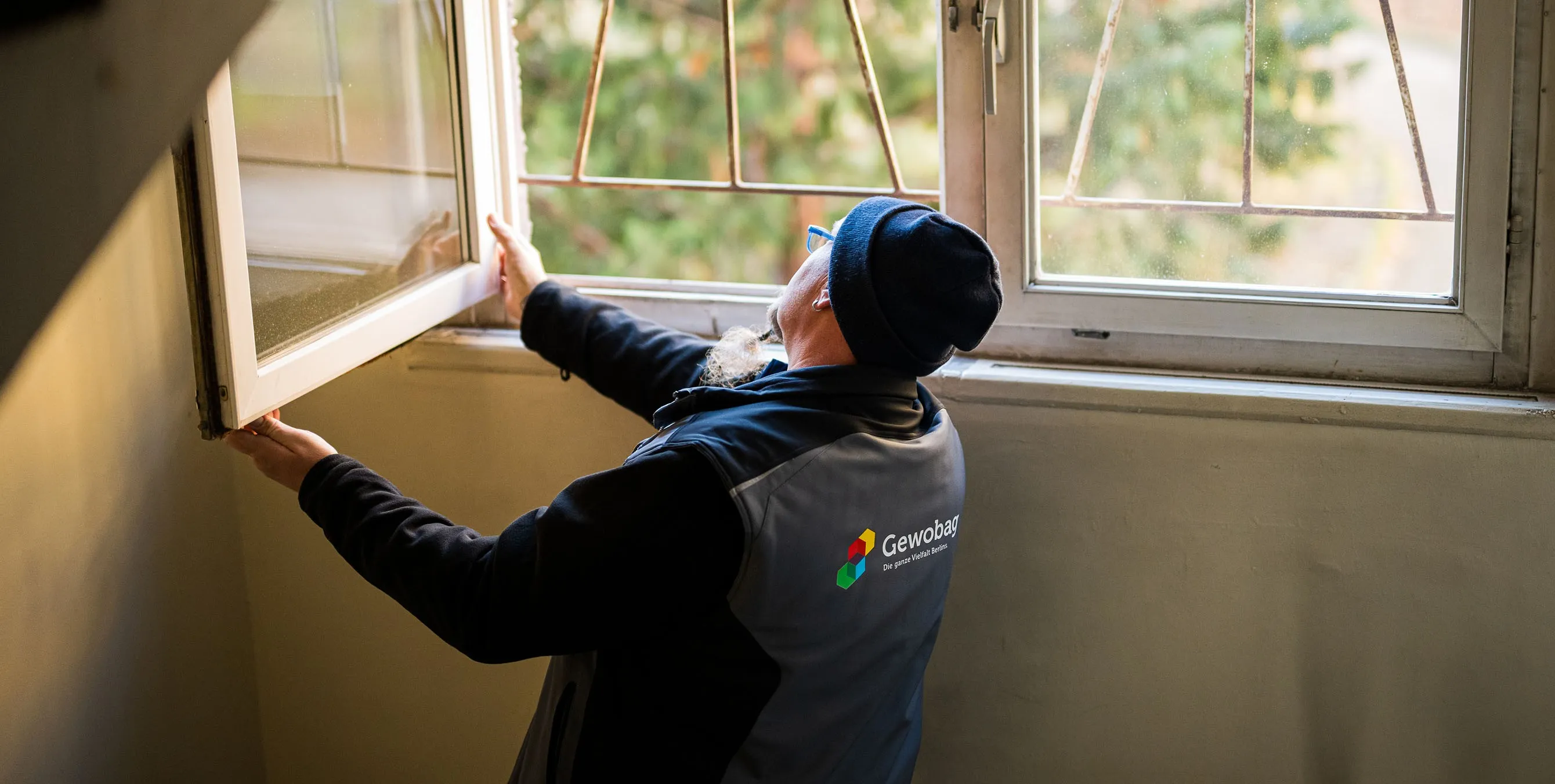 Ein Hauswart steht in einem Treppenhaus und überprüft ein halb geöffnetes Doppelfenster. Foto: City-Press GmbH